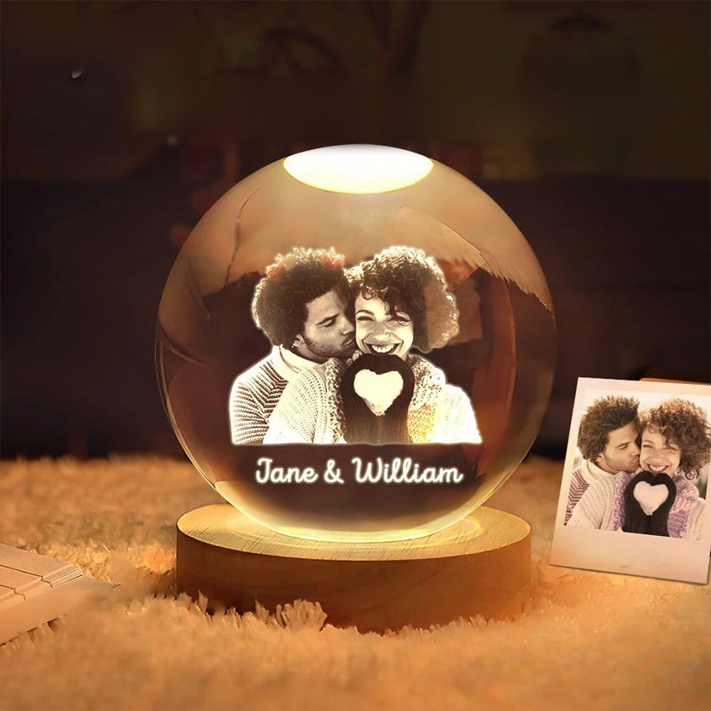 Crystal globe with a couple's photo and their names engraved, glowing on its wooden LED base